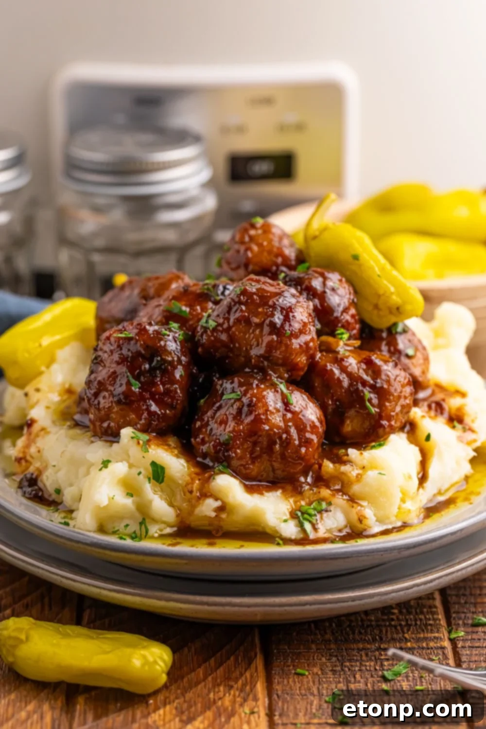 5 Ingredient Crockpot Mississippi Meatballs 23 Crockpot Mississippi Meatballs on a stack of plates with more peppers to side and CrockPot behind it on table