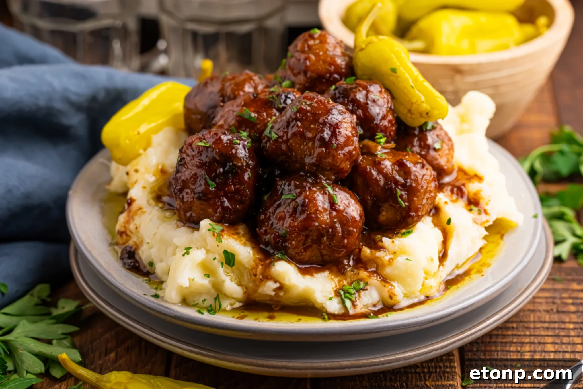 5 Ingredient Crockpot Mississippi Meatballs 24 Crockpot Mississippi Meatballs on a stack of plates with more peppers over mashed potatoes