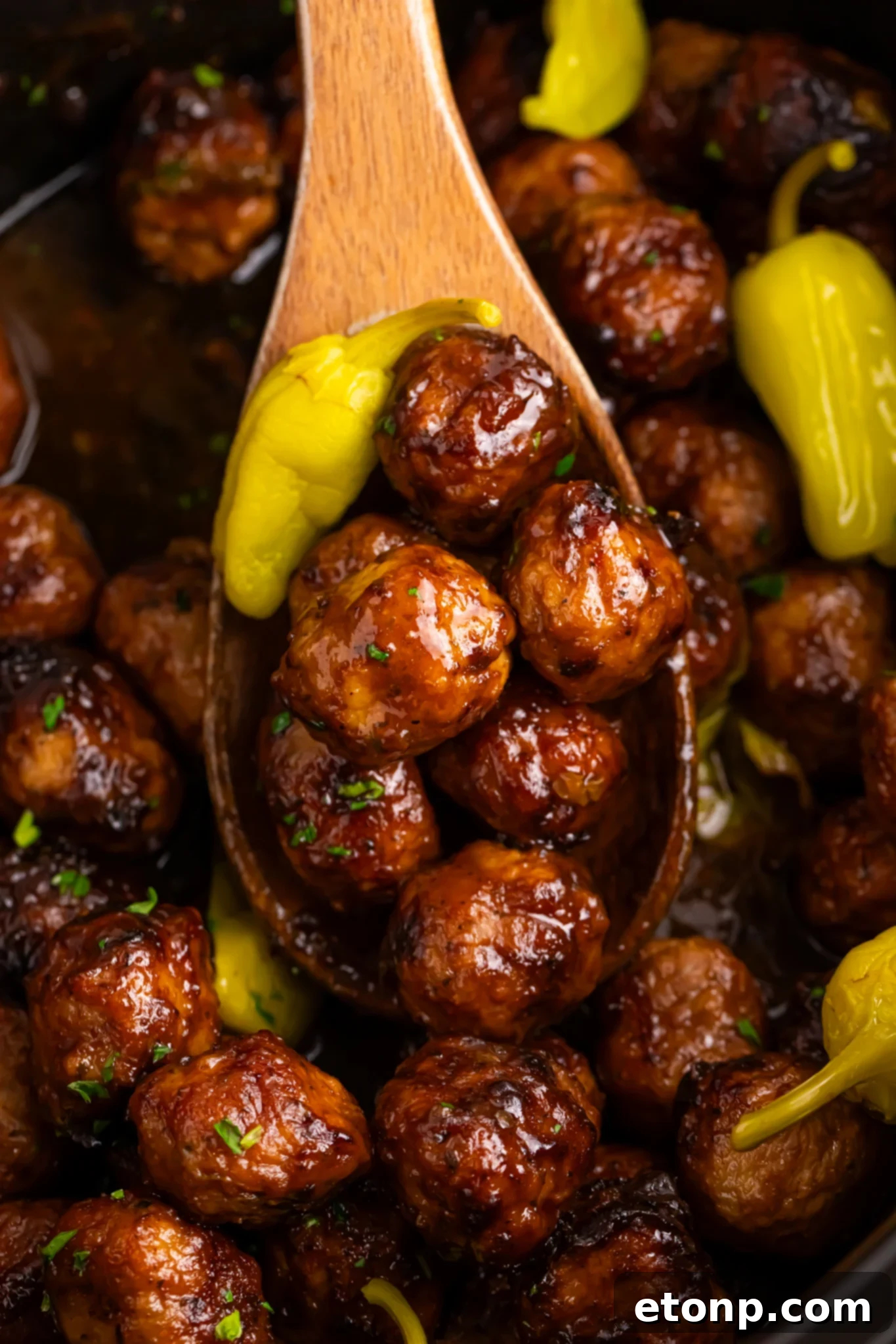 5 Ingredient Crockpot Mississippi Meatballs 4 wooden spoon being held above Crockpot with Mississippi meatballs in it