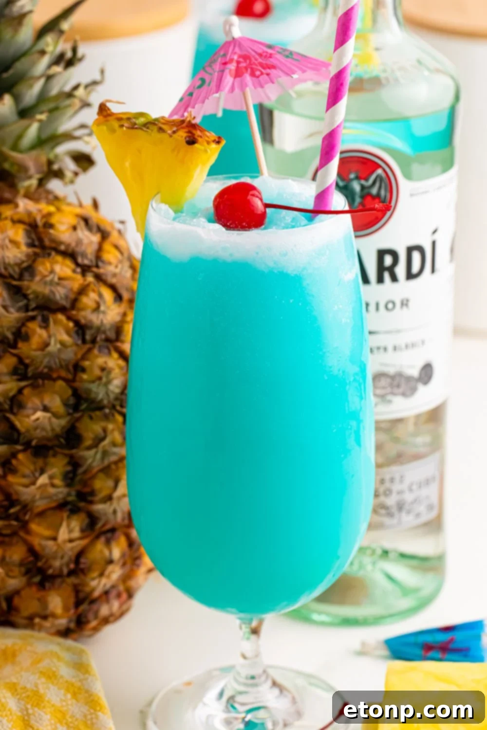 Frozen Blue Hawaiian Cocktail on table with rum and fruit around it on table