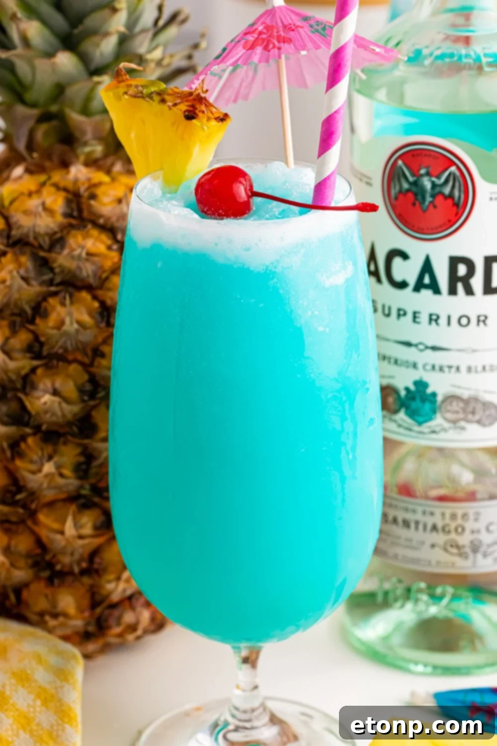 Frozen Blue Hawaiian Cocktail on table with a pineapple and bottle of rum behind it on table 