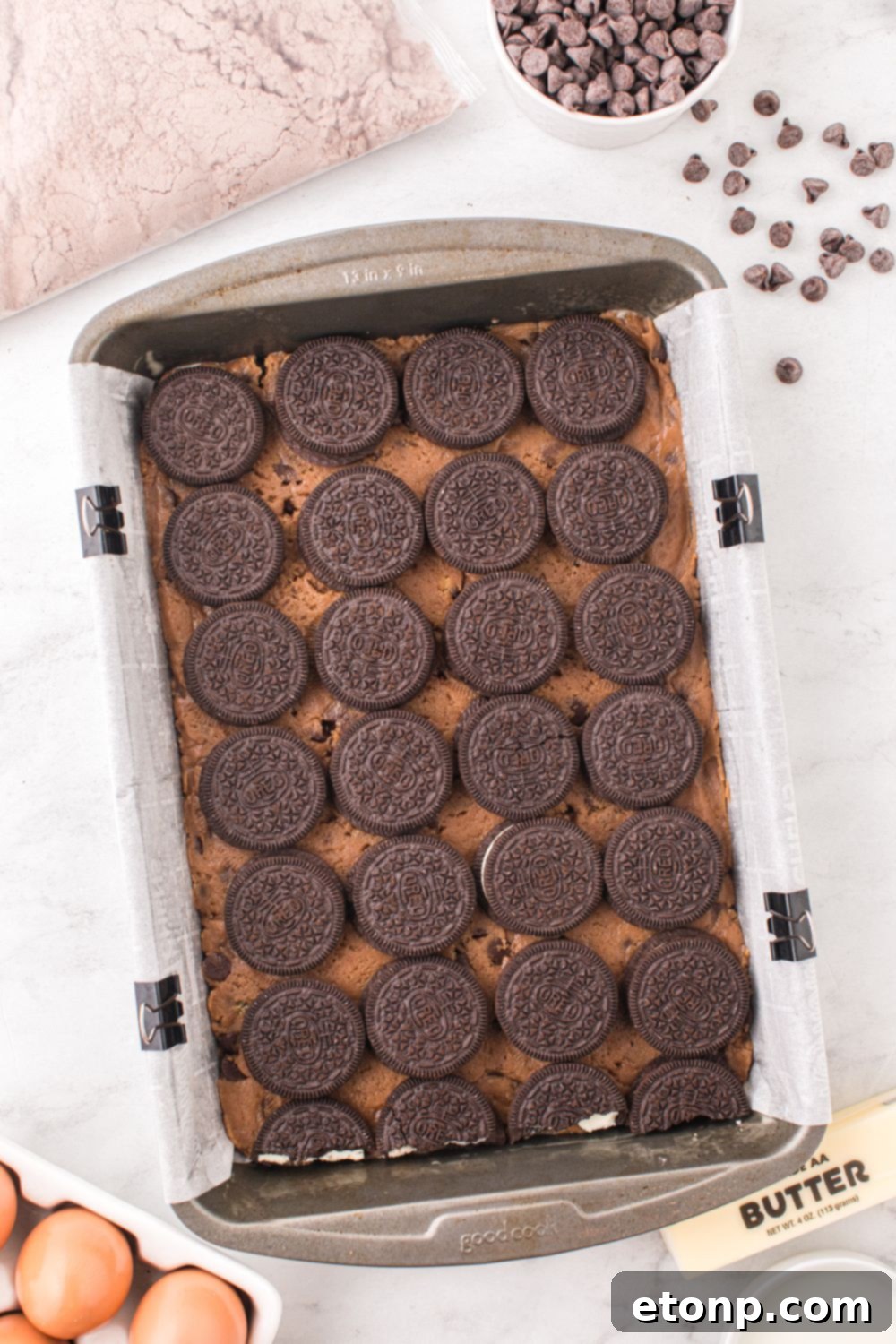 chocolate chip cookie dough topped with Oreo cookies on top in a baking tray 