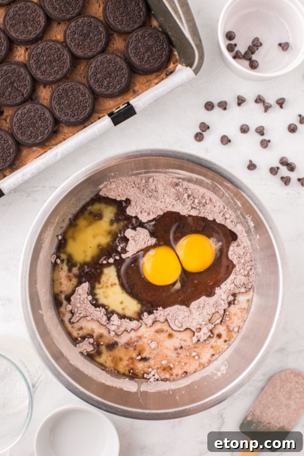 Slutty Brownies being assembled on table with a brownie batter in a bowl on table 