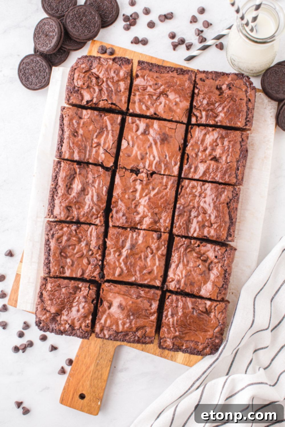 Slutty Brownies sliced and placed on a tray on table with chocolate chips and cookies 