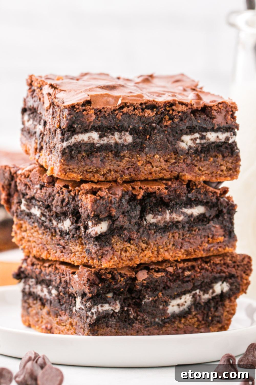 Slutty Brownies stacked on plate with some chocolate chips around table 