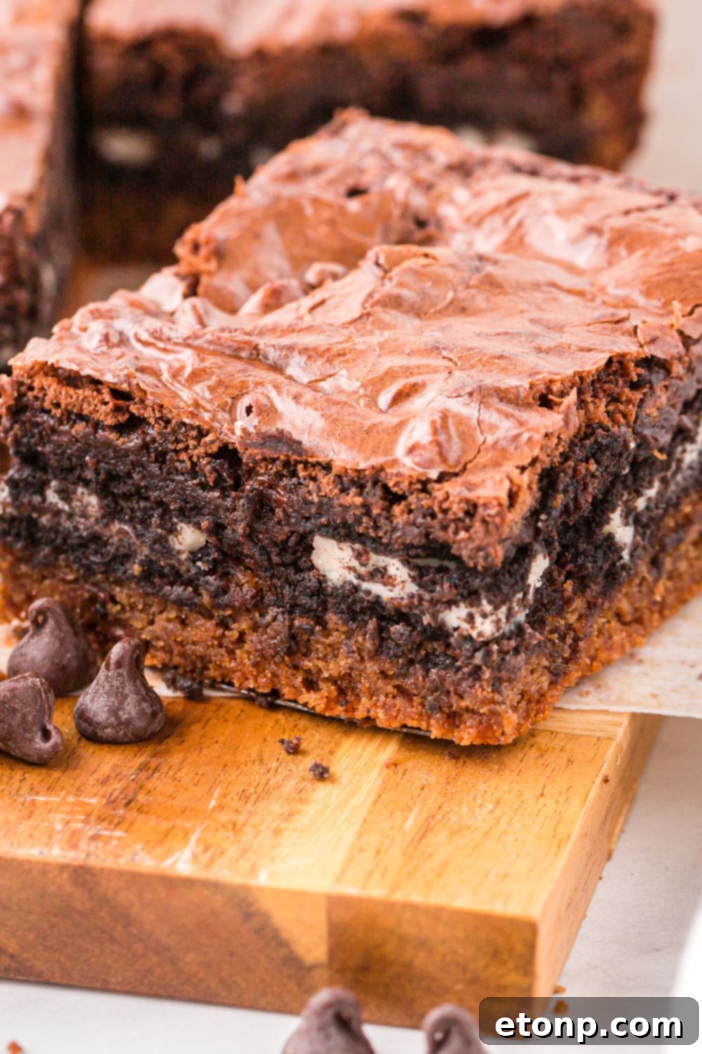 wooden table with Slutty Brownies spread out on tray and a few chocolate chips to the side 