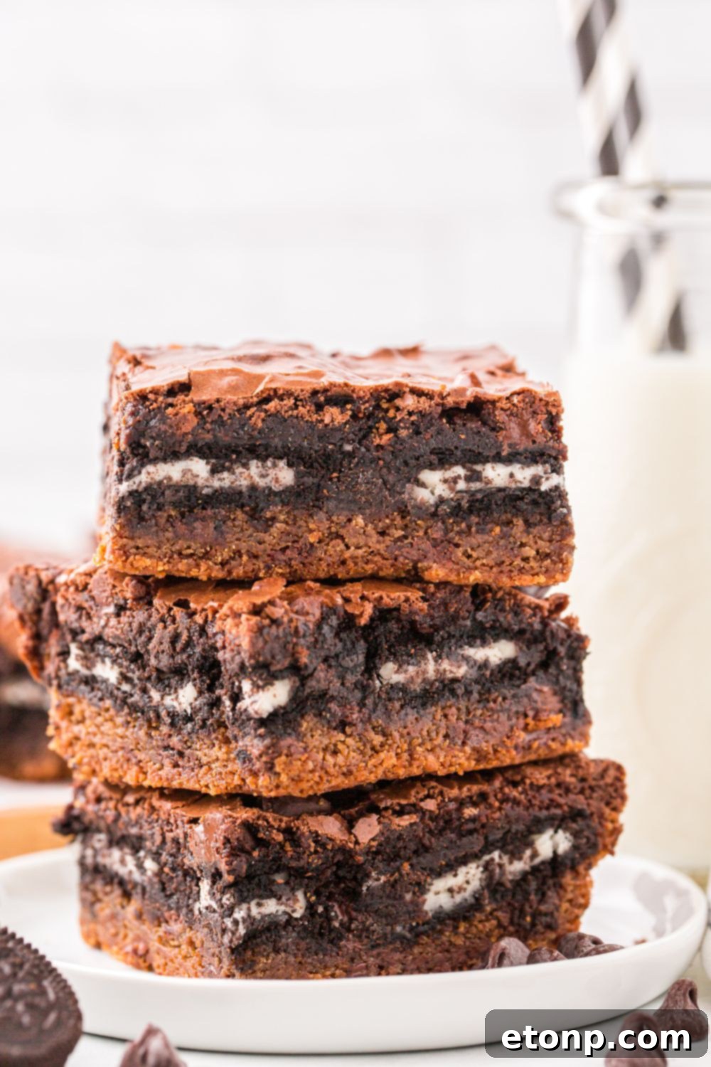Slutty Brownies stacked on top of one another with a glass of milk behind it on table 