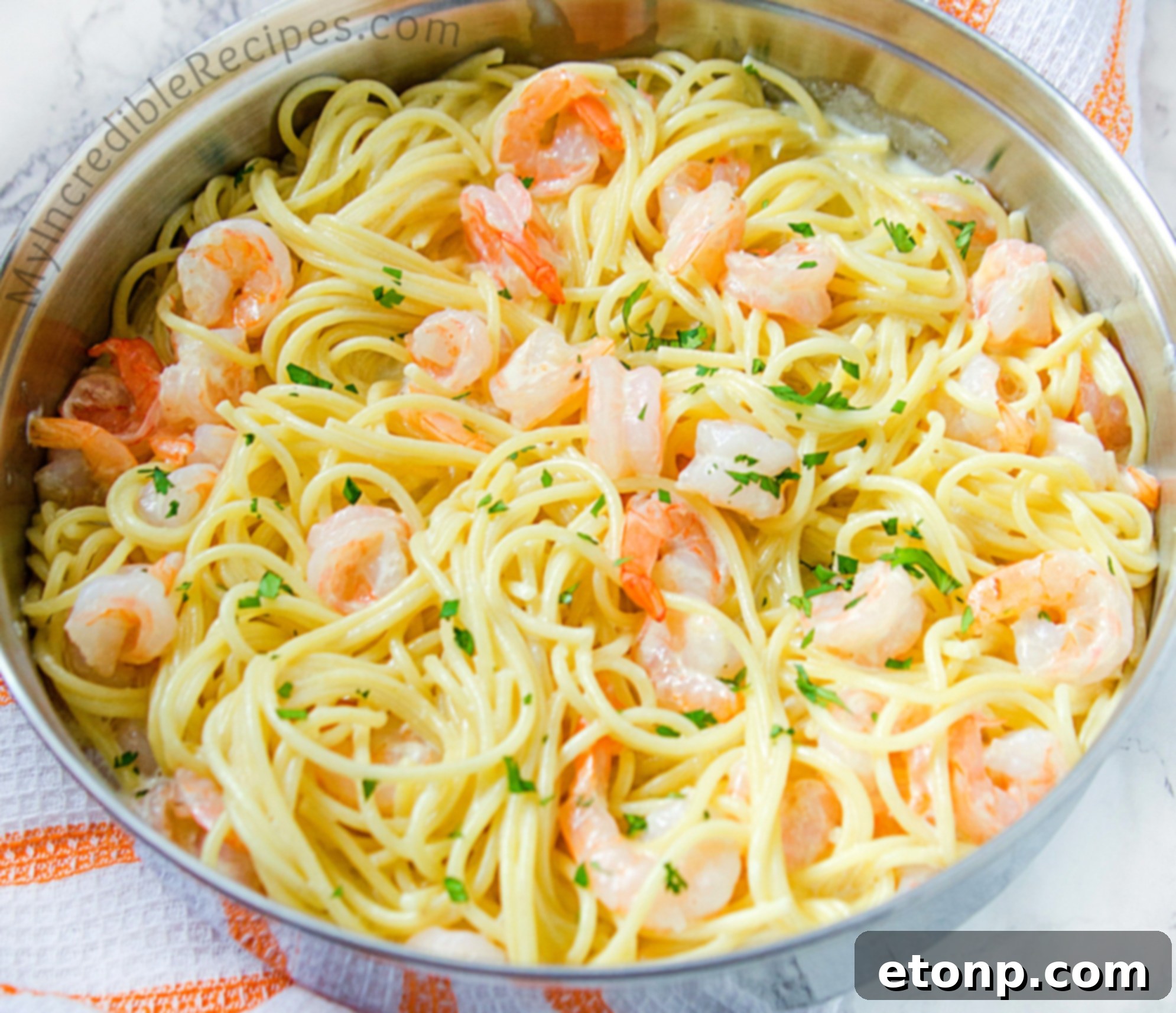 Top-down view of the pan, showcasing cooked shrimp, minced garlic, and butter, forming the base of the pasta sauce.