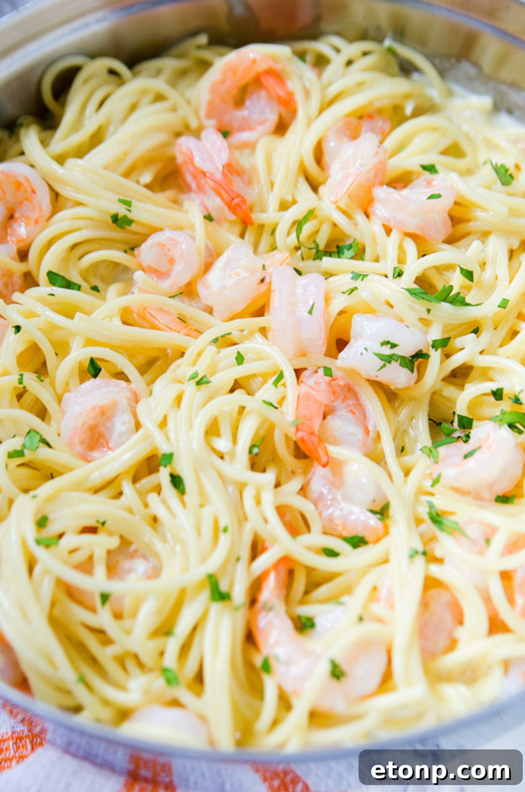 Close-up of a skillet filled with a creamy, garlicky sauce, with visible minced garlic pieces, before adding pasta.