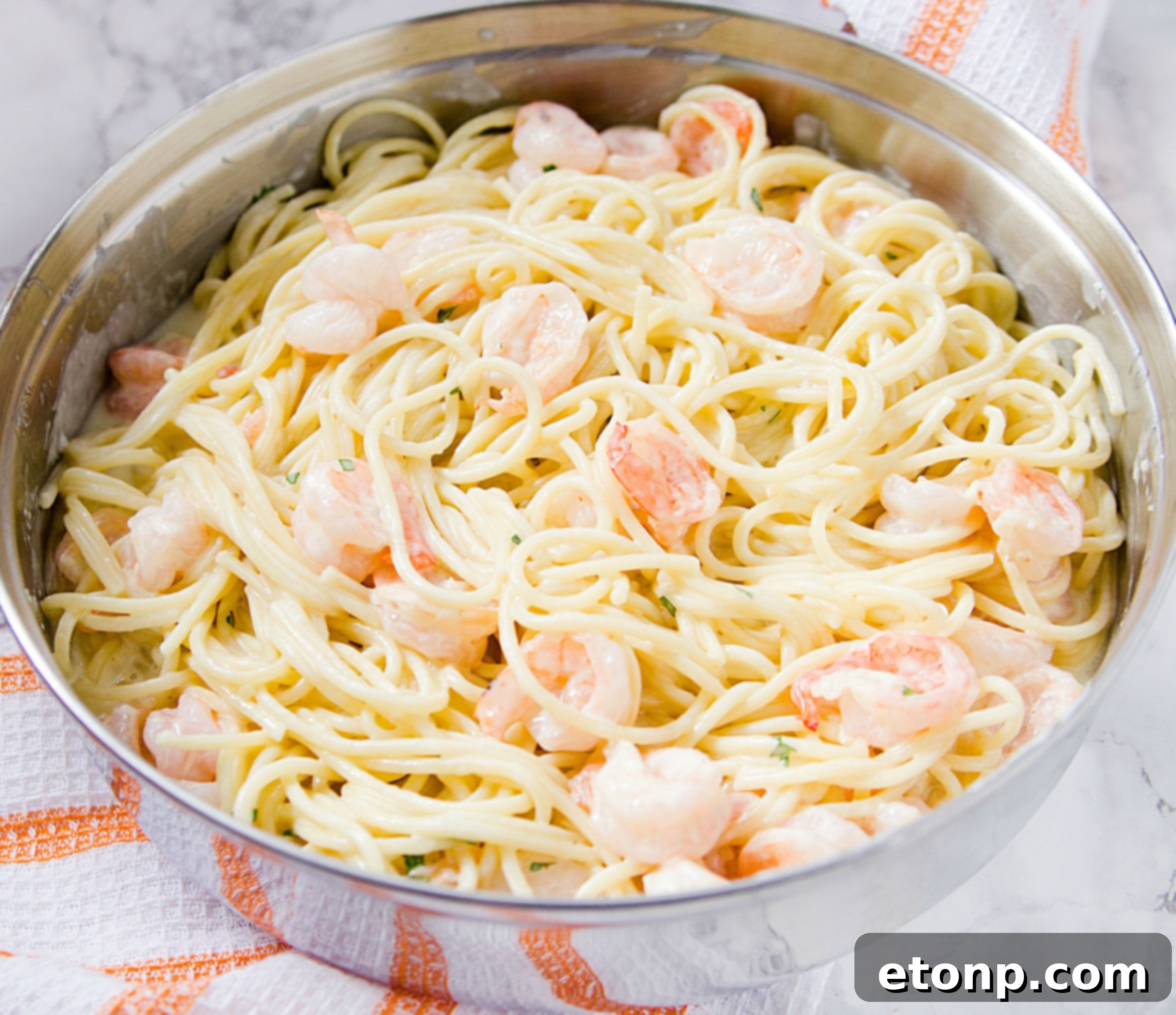 A close-up shot of the finished four cheese garlic shrimp pasta, showcasing the creamy sauce and succulent shrimp, garnished with fresh herbs.