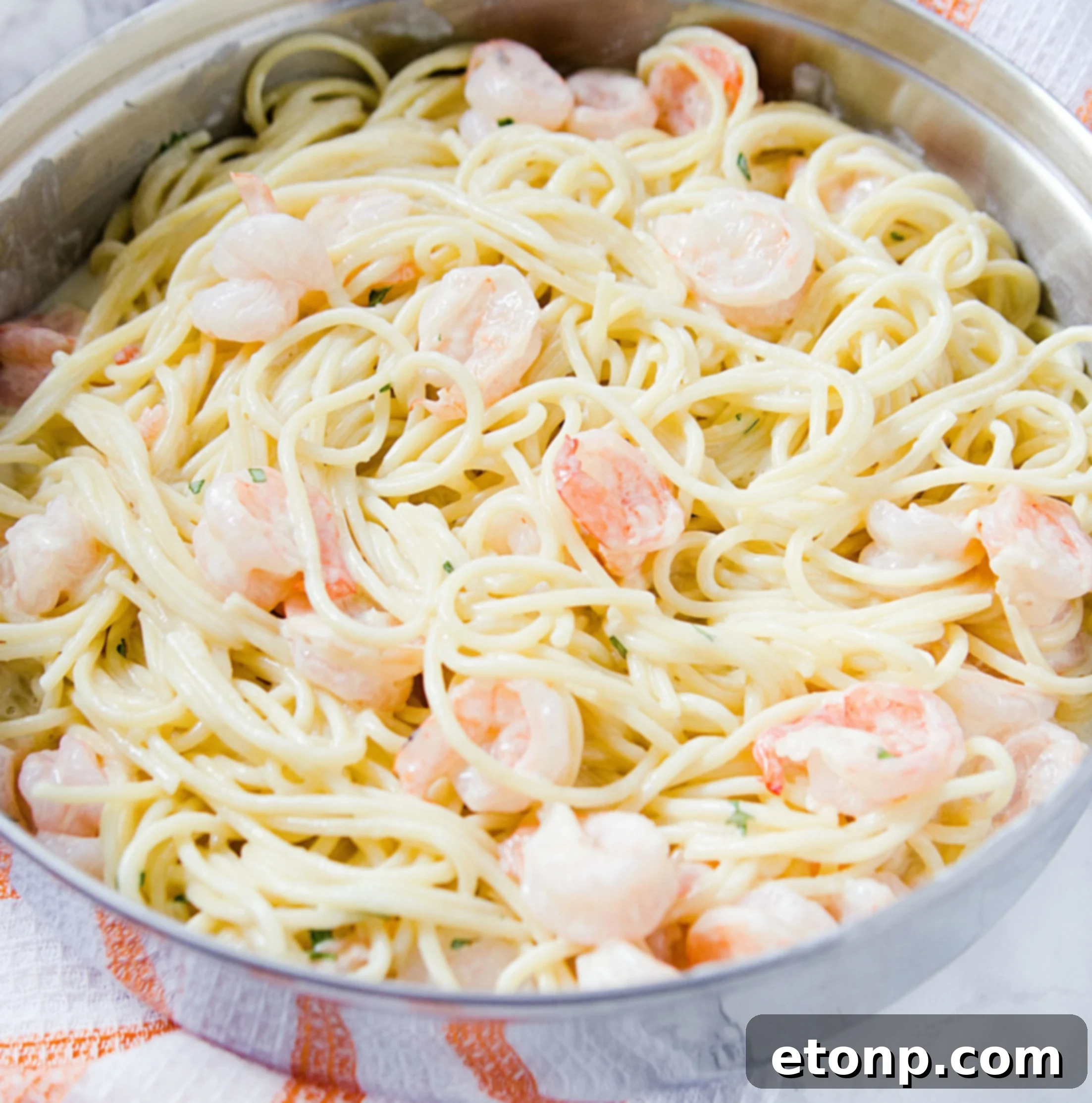 Another perspective of the creamy garlic shrimp pasta, emphasizing the texture of the sauce and the integration of ingredients.