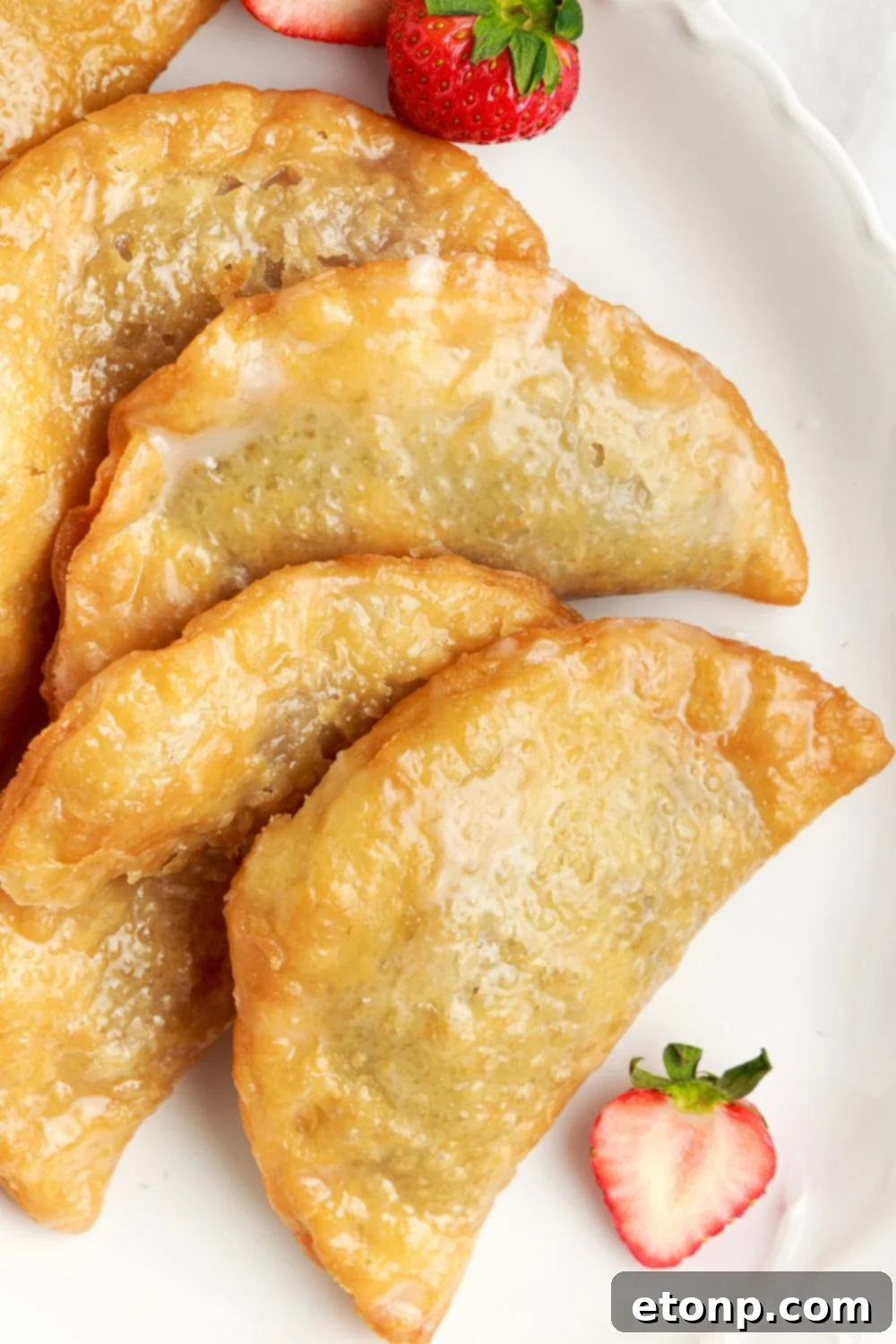 A charming arrangement of Deep Fried Strawberry Cheesecake Pies artfully laid out on a tray, with fresh strawberries scattered around the table.