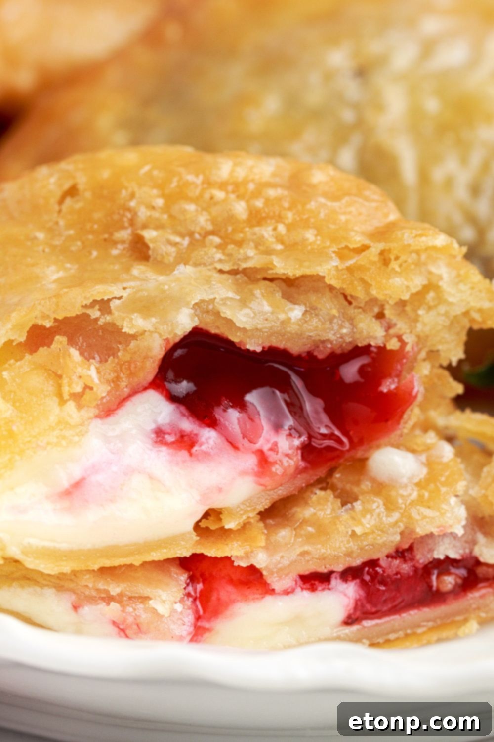 A Deep Fried Strawberry Cheesecake Pie placed on a plate, torn apart to expose the luscious creamy filling, with fresh strawberries positioned to the side.