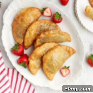 Deep Fried Strawberry Cheesecake Pies on table on a tray with fresh strawberries on plate