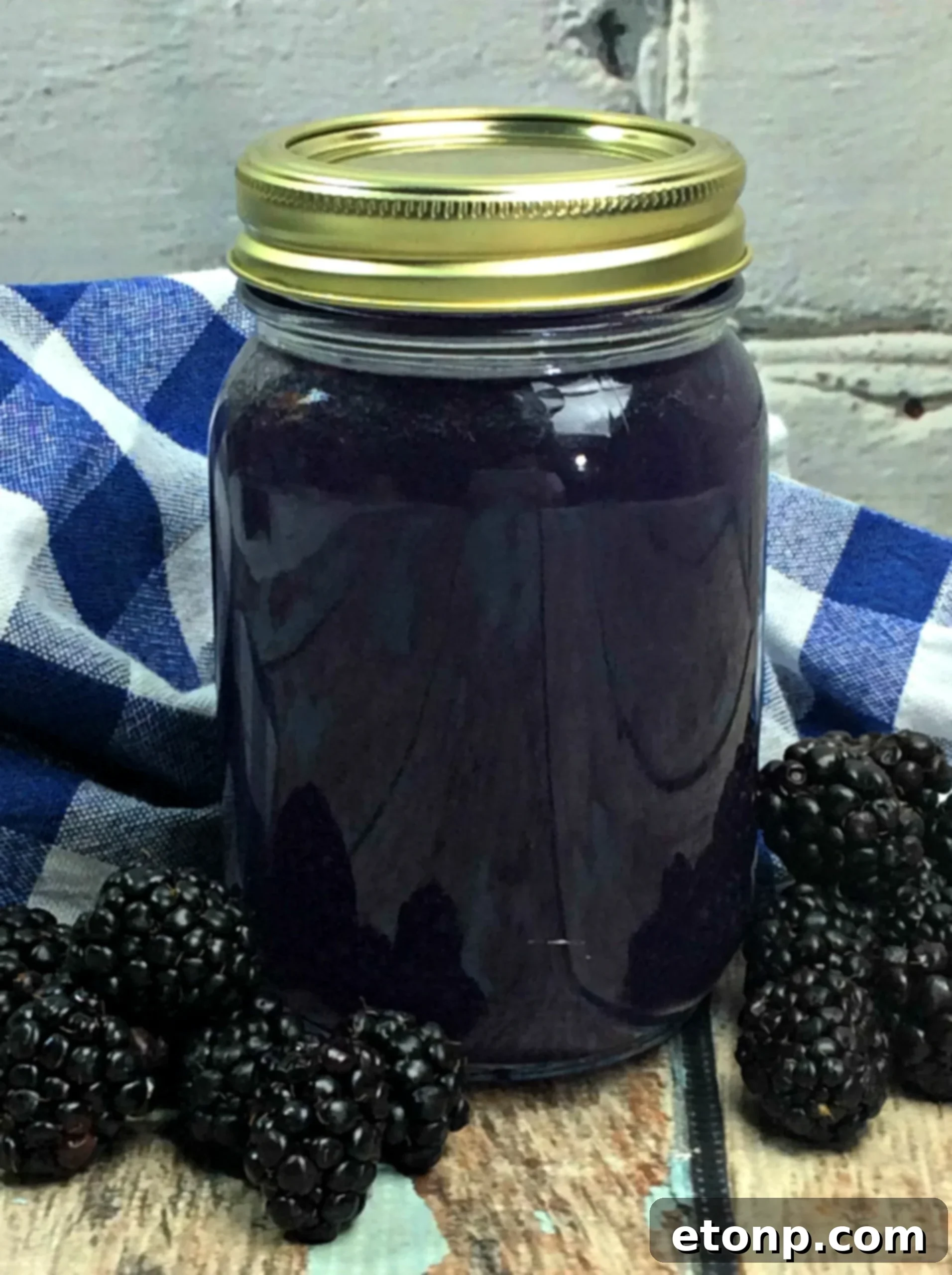 Homemade Blackberry Moonshine in a mason jar, garnished with fresh blackberries and a lime wedge, ready to be enjoyed.
