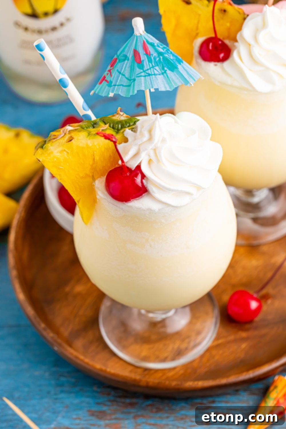 Frozen Malibu Piña Colada on table with pineapple wedge and umbrella