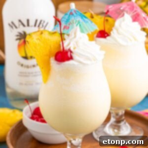 Frozen Malibu Piña Coladas in glasses with little umbrellas, pineapple slices and cherries
