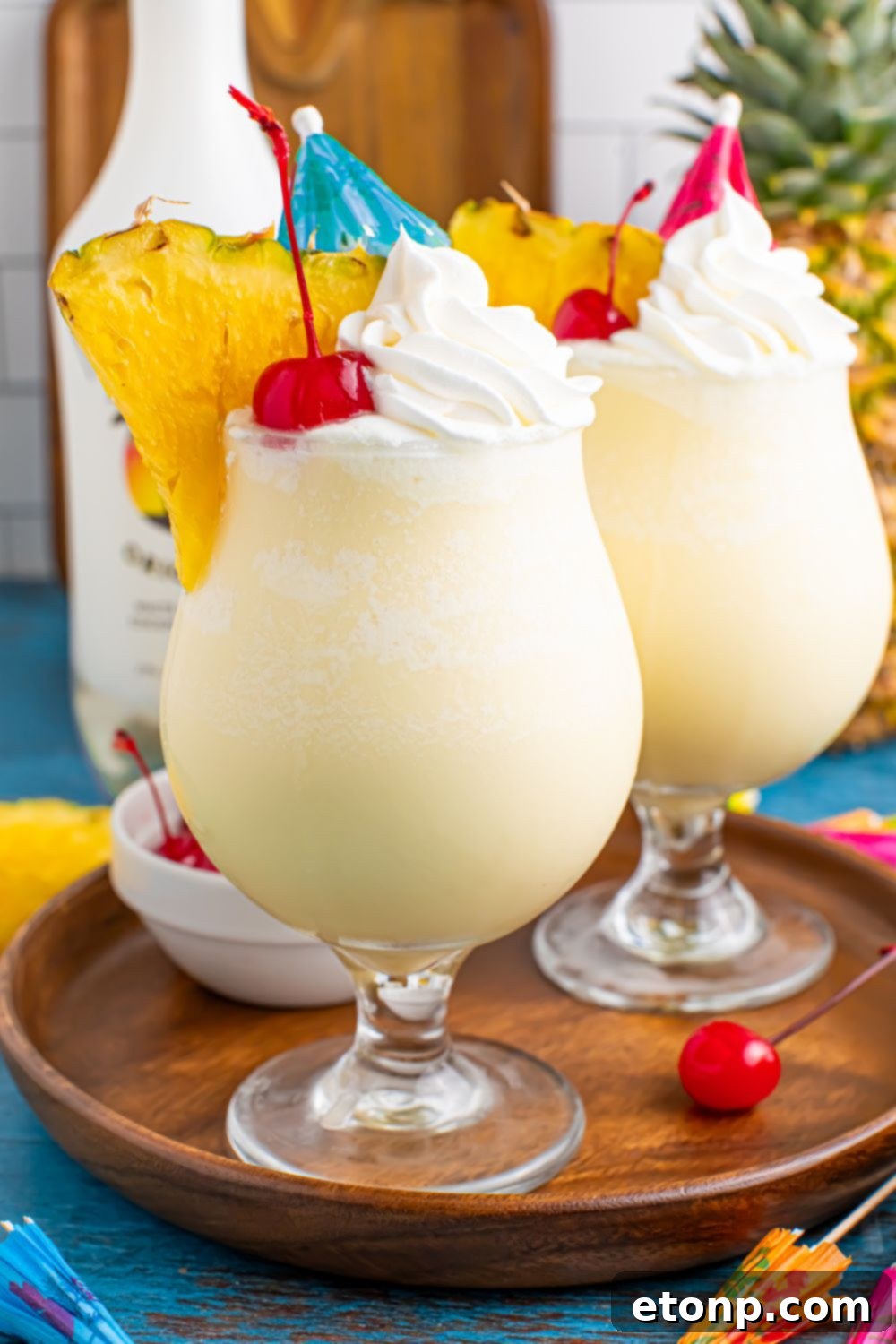 Frozen Malibu Piña Coladas in glasses on table with a bottle of malibu behind the drinks
