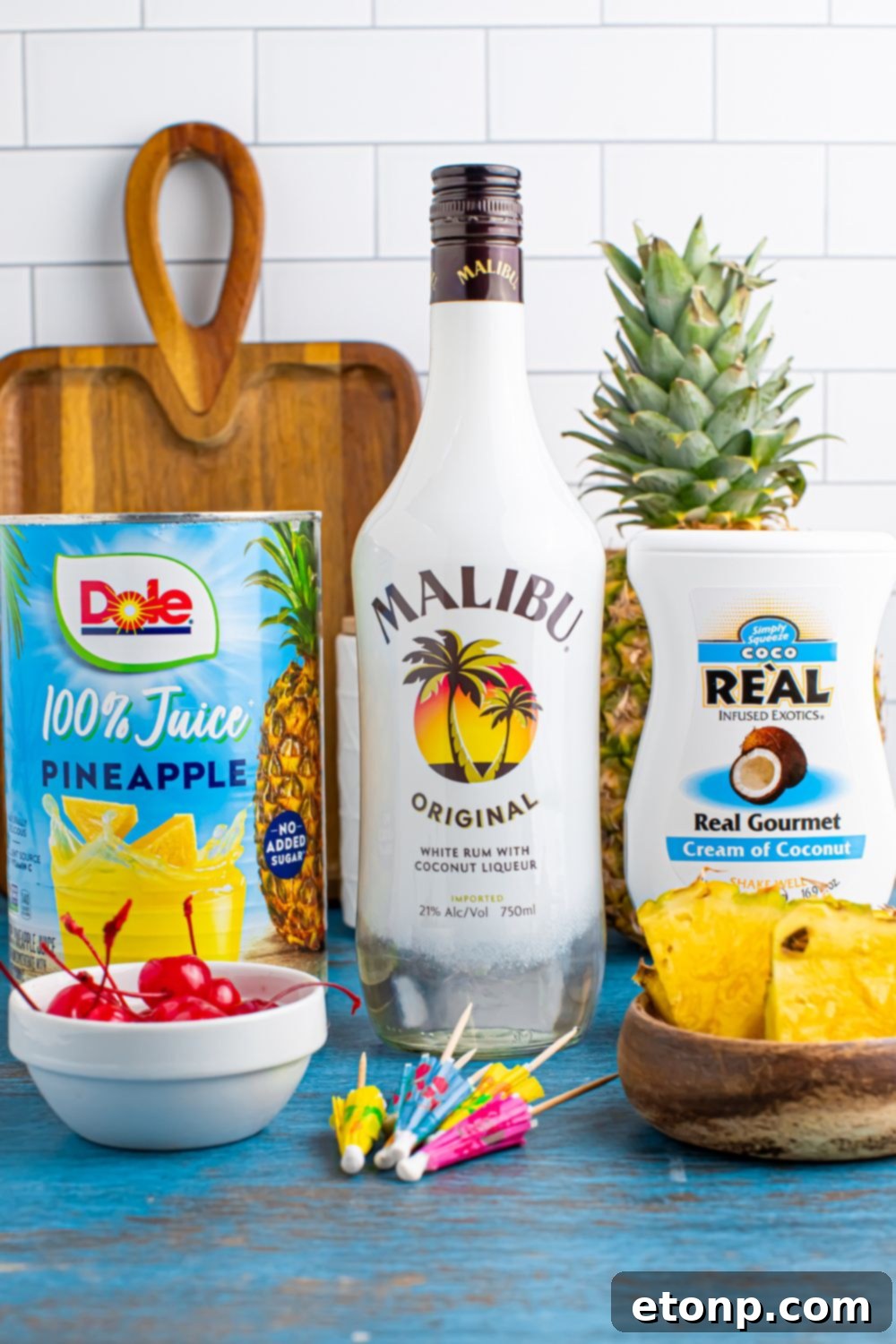 ingredients to make Frozen Malibu Piña Colada sitting on table with a cutting board sitting on table