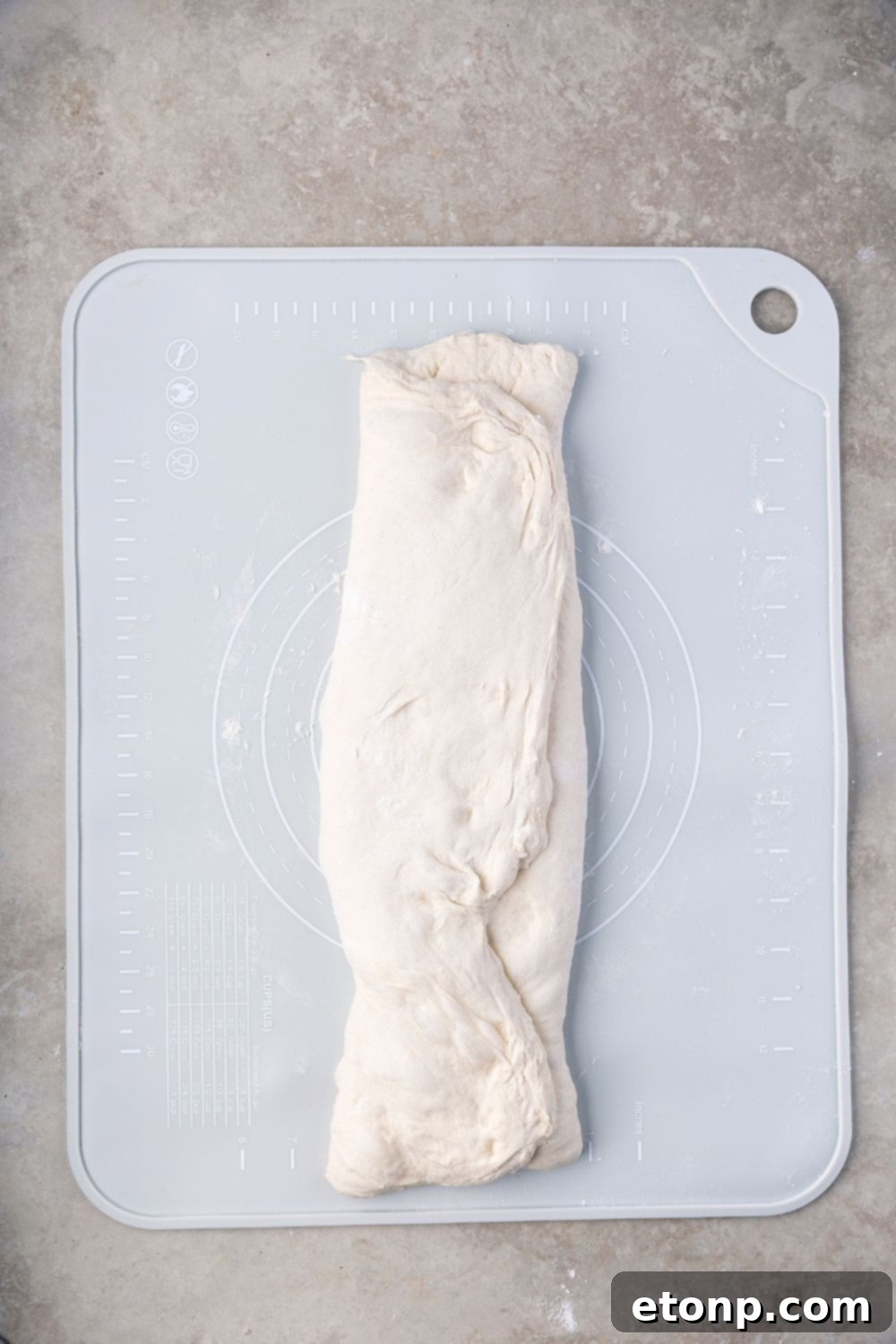 Homemade Sourdough Bread dough folded up on a cutting board on table 