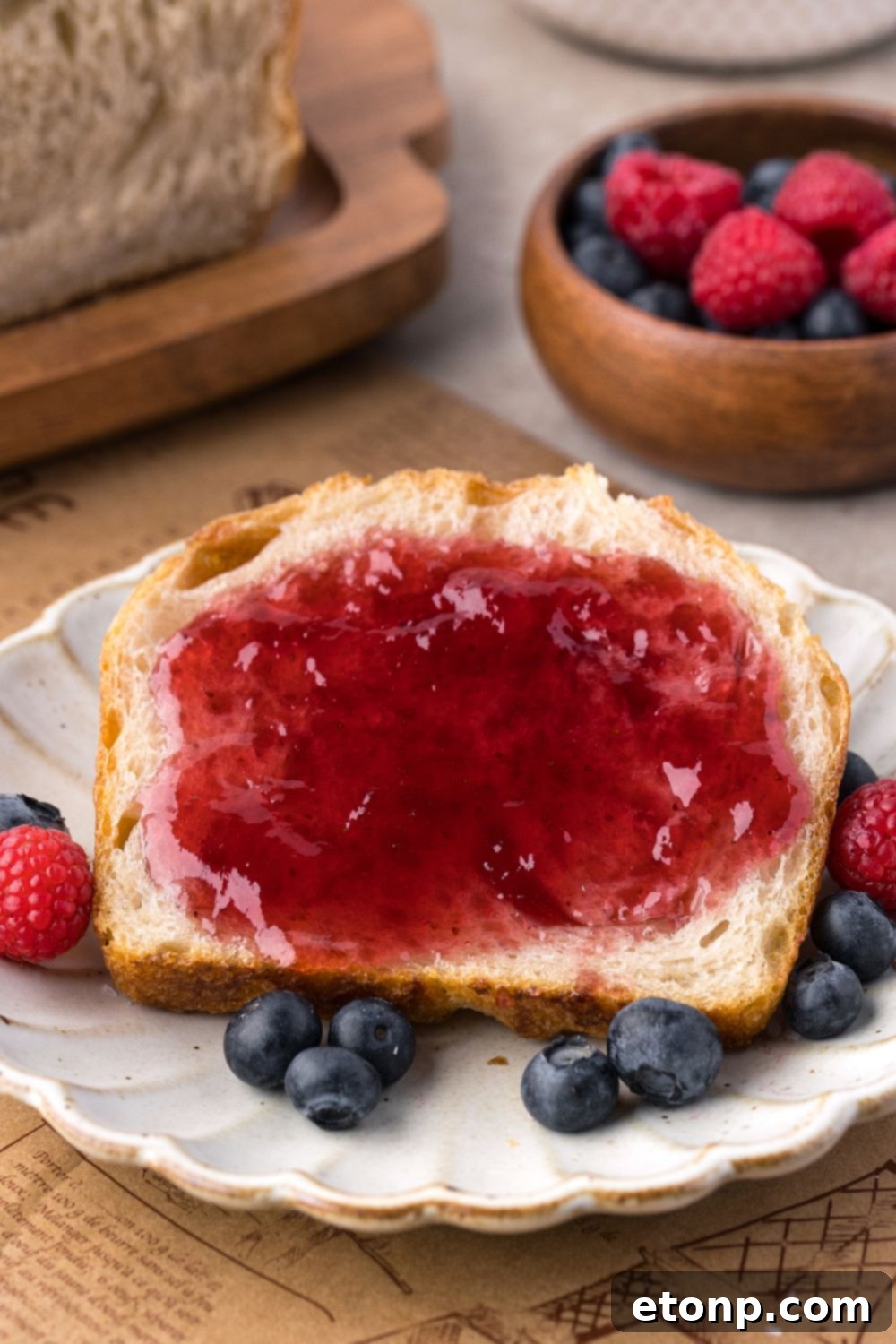 Homemade Sourdough Bread sliced on plate with jam, and berries around it 