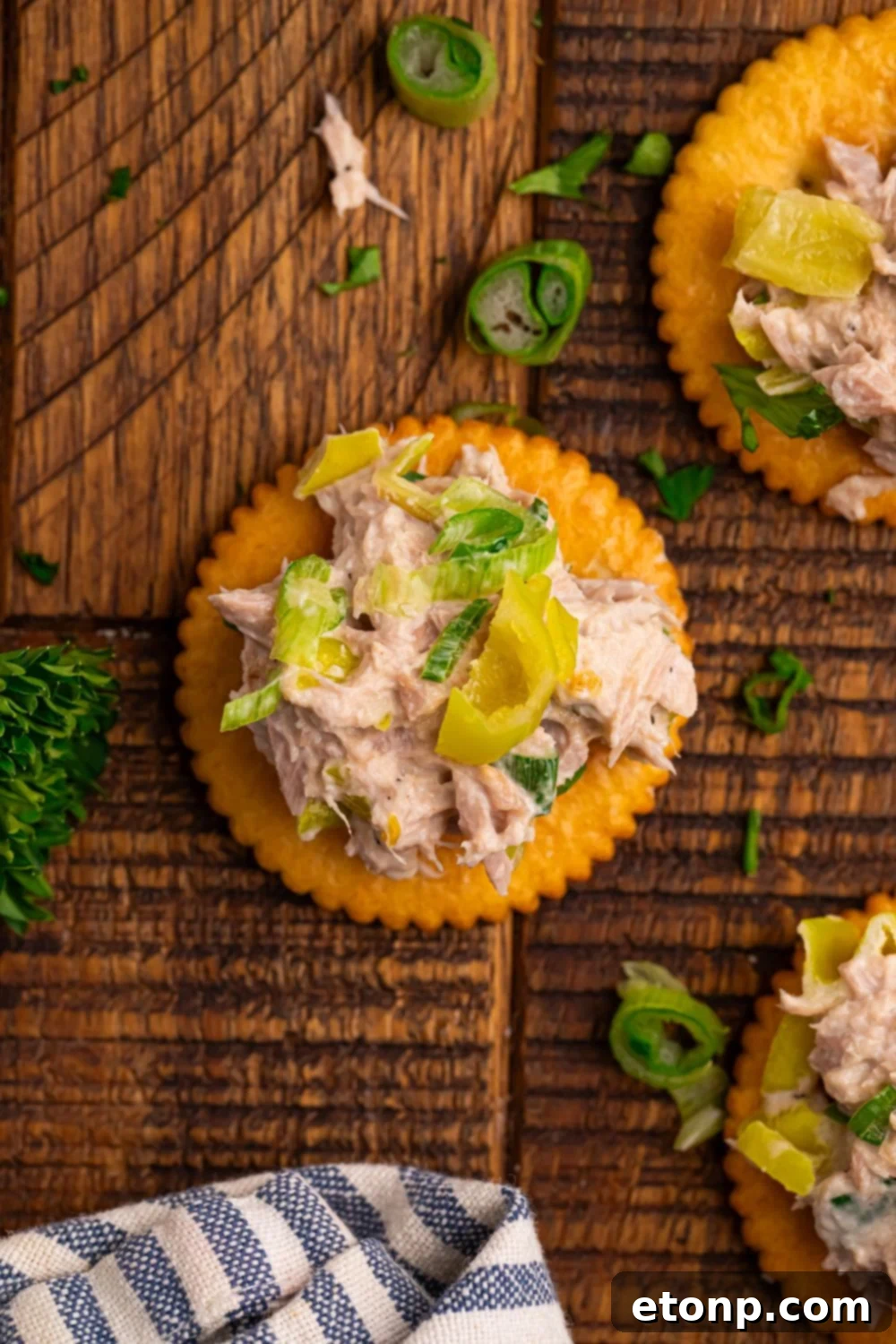 Pepperoncini Ranch Tuna Salad on top of crackers with fresh parsley and green onions on a table
