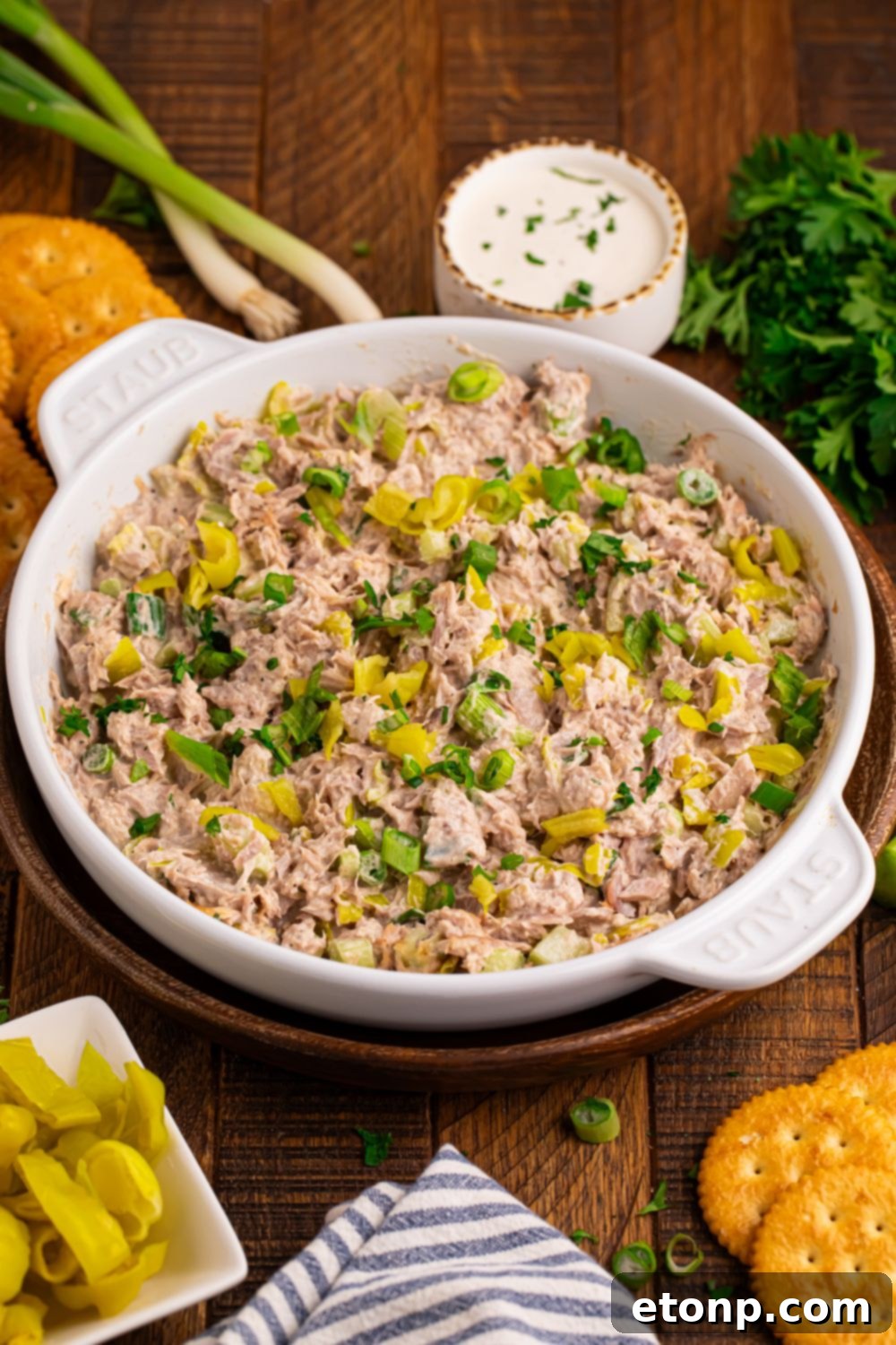 Table setup with fresh green onions, a bowl of ranch dressing, crackers, and a large bowl of Pepperoncini Ranch Tuna Salad
