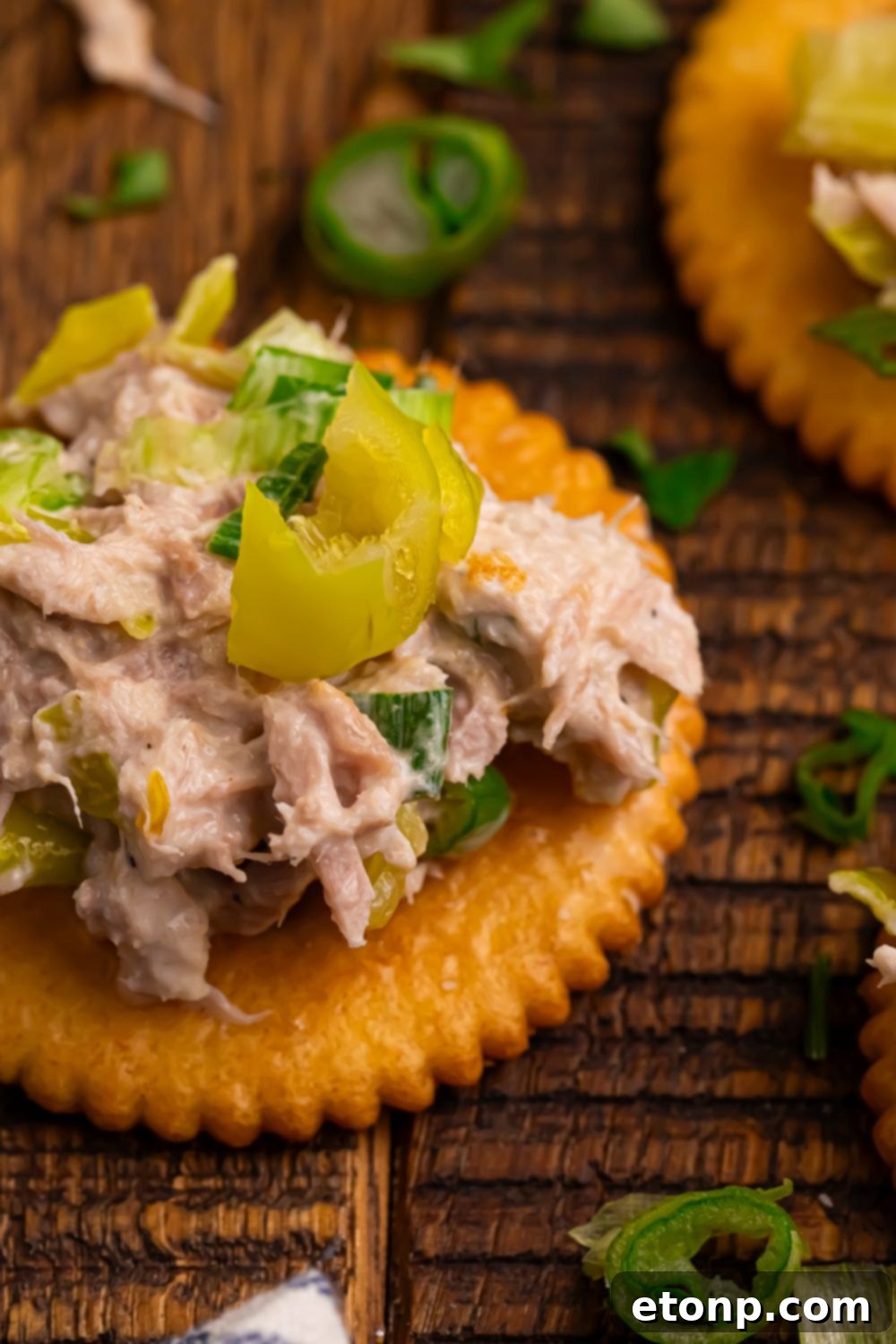 Pepperoncini Ranch Tuna Salad on a cracker sitting on a rustic wooden table