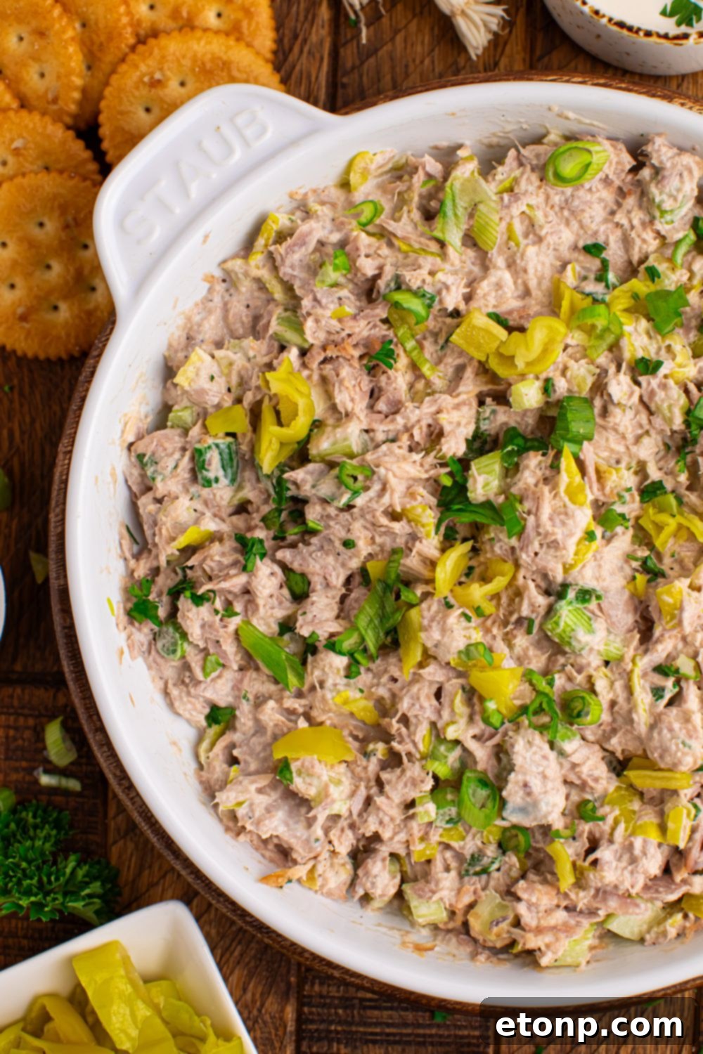 Pepperoncini Ranch Tuna Salad in a white bowl on a table, with crackers and more pepperoncinis in a small bowl on the side