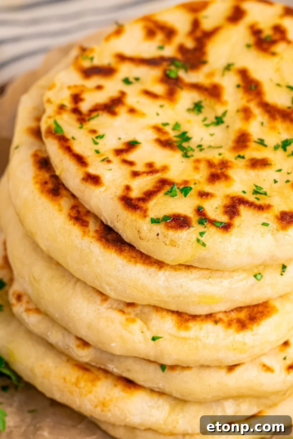 3 Ingredient Flatbread stacked on table with parsley and butter 