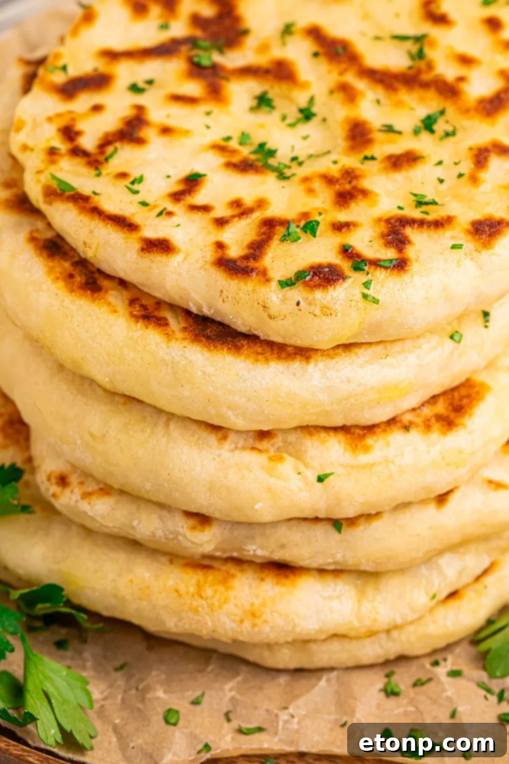 3 Ingredient Flatbread in a stack on a tray with parsley chopped sprinkled around table 