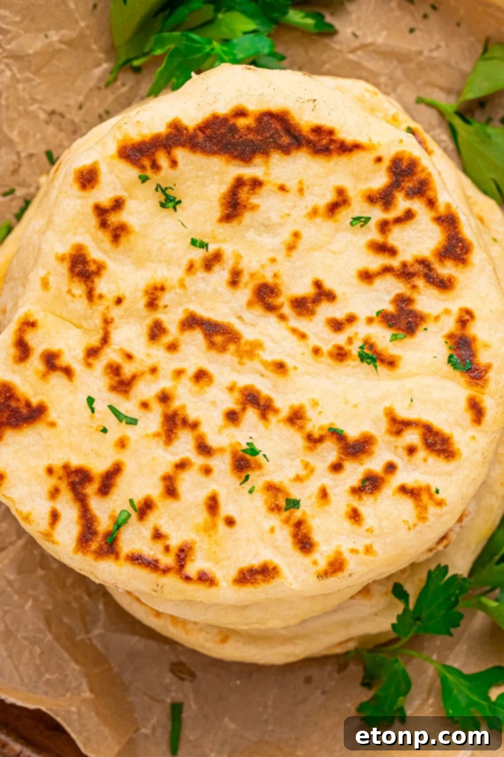 3 Ingredient Flatbreads stacked on top of one another on table with parsley around it 