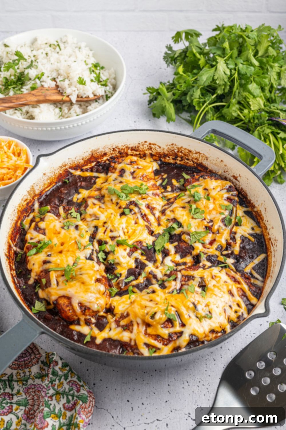 One Pan Cheesy Salsa Chicken 3 Cheesy Salsa Chicken in a skillet on table with parsley and rice and cheese in bowls