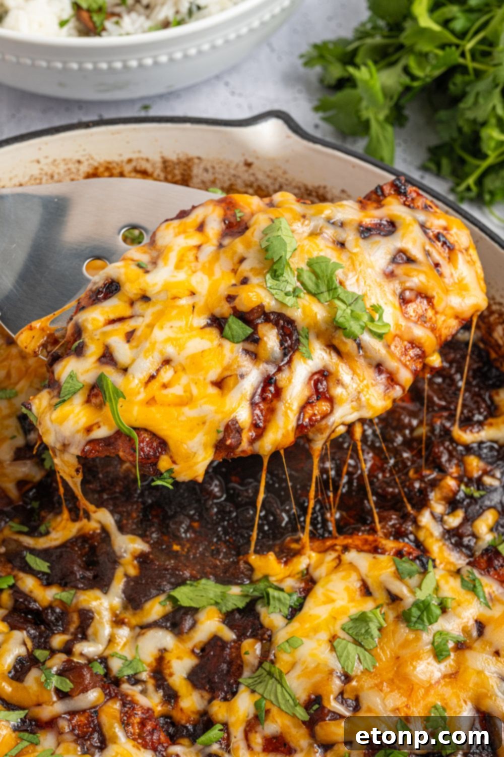 One Pan Cheesy Salsa Chicken 21 Cheesy Salsa Chicken being lifted out of pan that is garnished with parsley