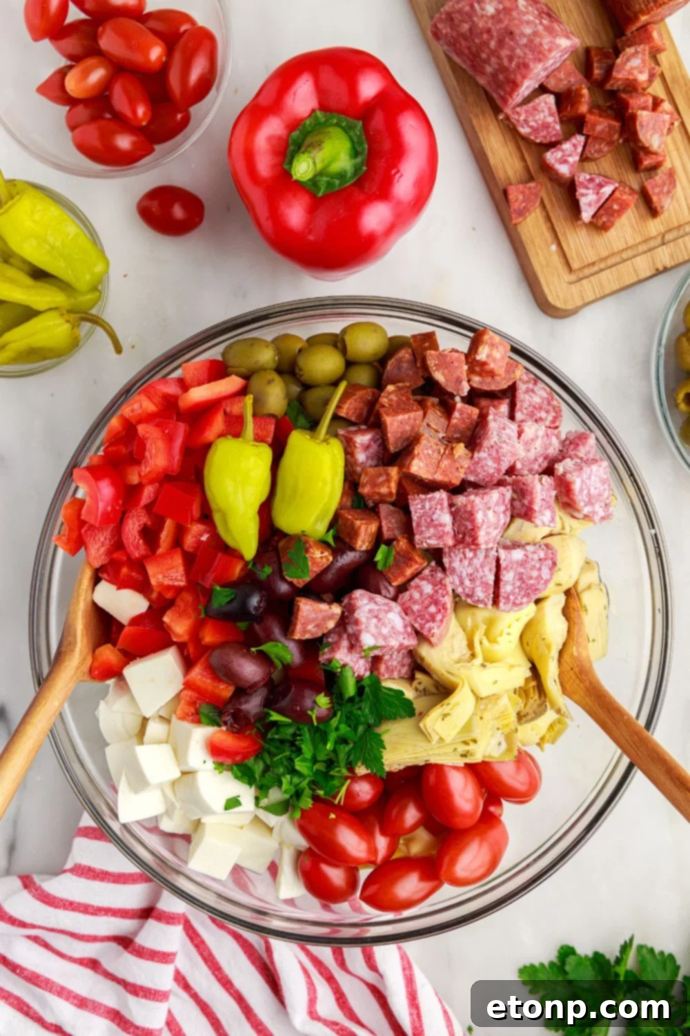 A close-up of the mixing process of the Antipasto Tortellini Pasta Salad in a glass bowl.