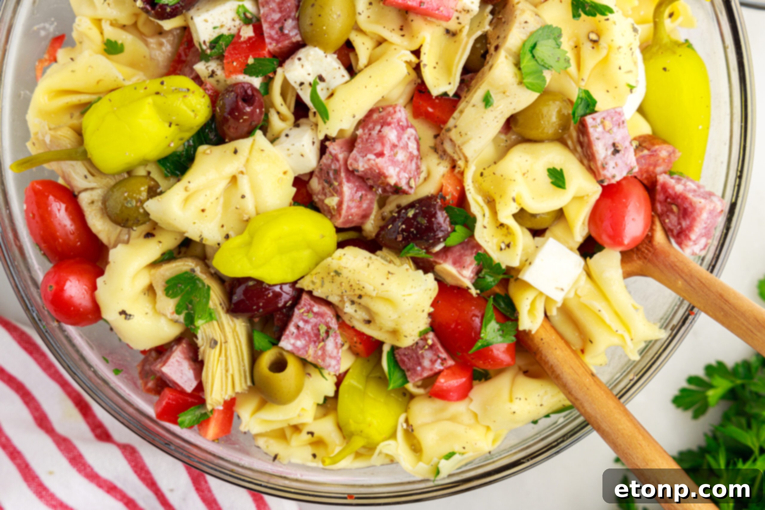 Overhead shot of the Antipasto Tortellini Pasta Salad in a glass serving bowl, highlighting the colorful medley of ingredients.