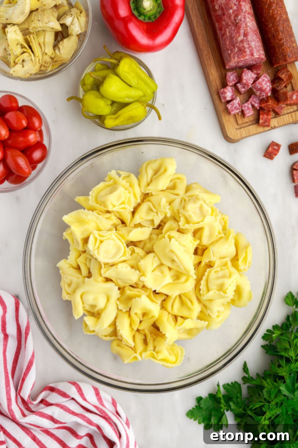 Freshly cooked tortellini pasta in a glass bowl, ready for mixing into the salad.