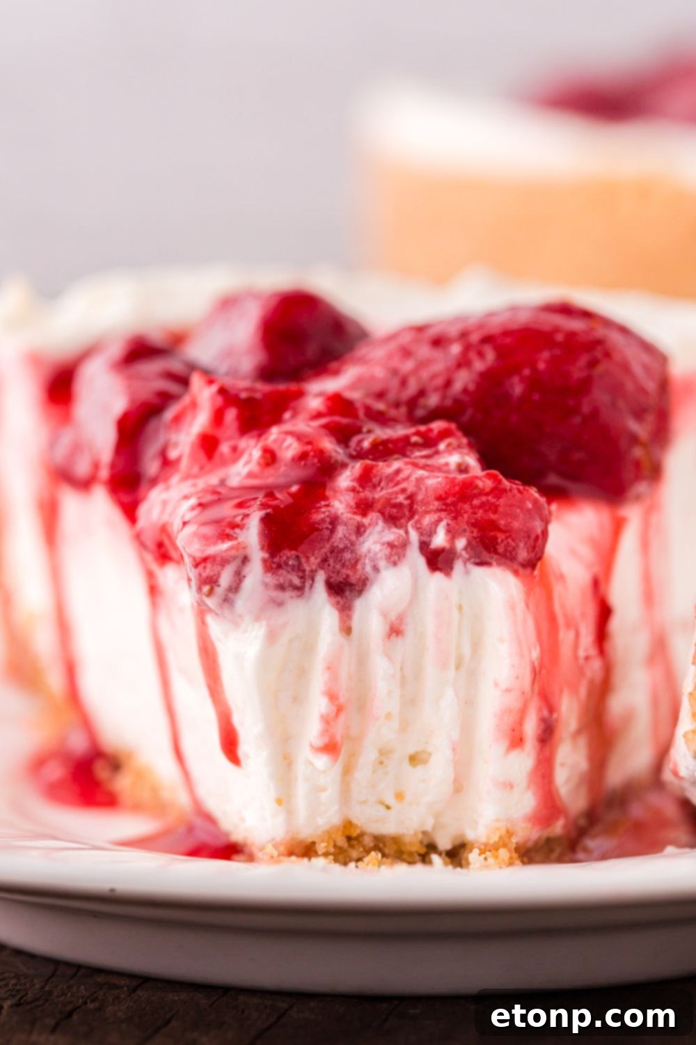 A perfectly sliced No Bake Strawberry Cheesecake resting on a plate, with a small bite taken out, highlighting its delicious layers.
