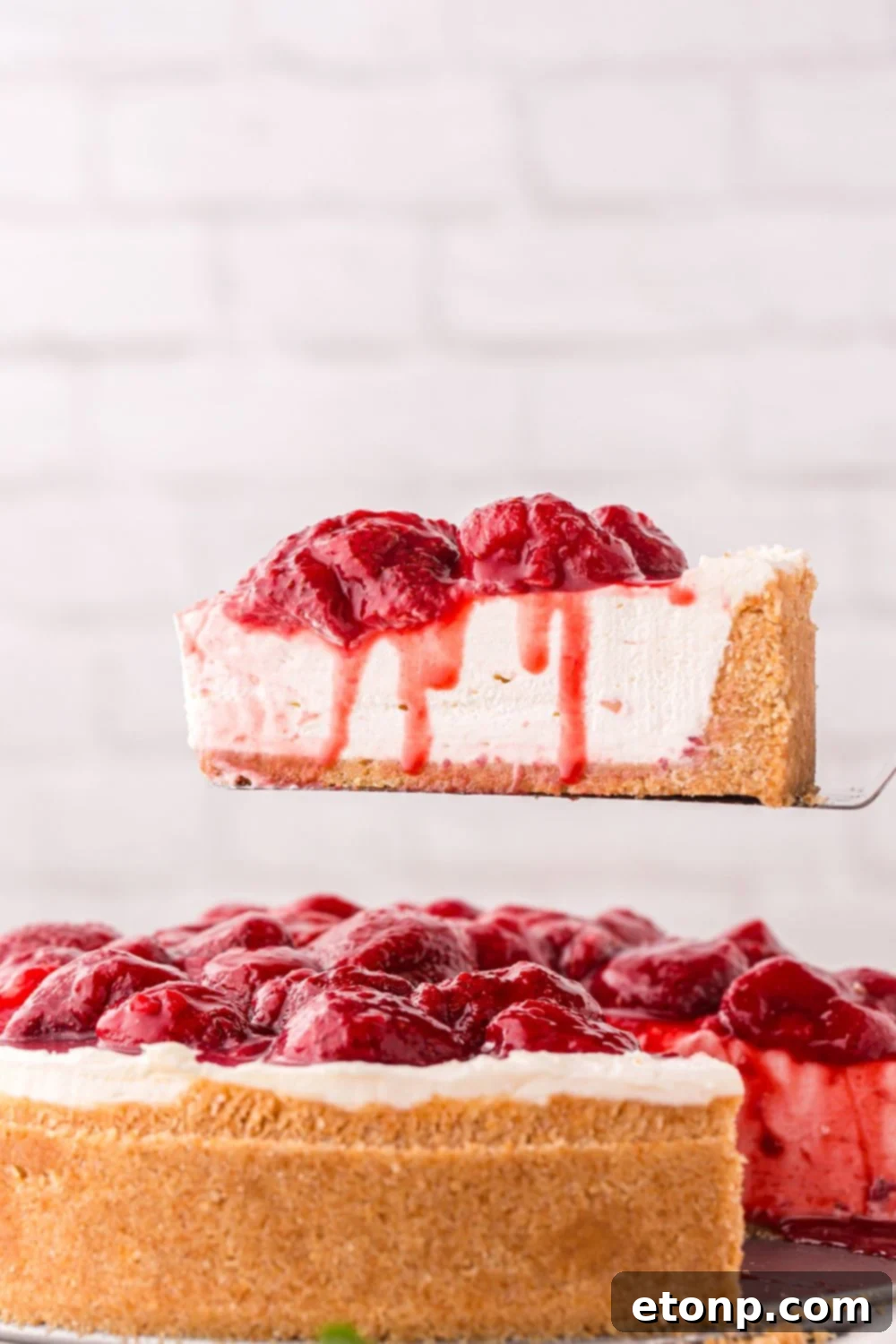 A perfectly portioned slice of No Bake Strawberry Cheesecake being gracefully lifted with a spatula, showcasing its impeccable layers and inviting presentation.