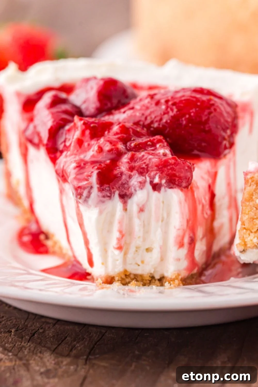 A single, delectable slice of No Bake Strawberry Cheesecake on a plate, with a bite taken out, showing the perfect layers and creamy filling.