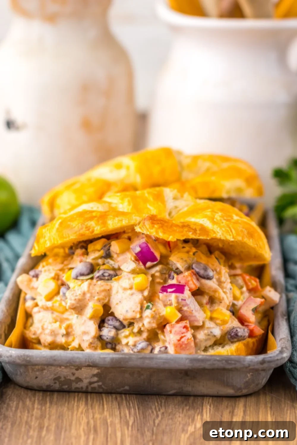 View of Creamy Taco Chicken Salad sandwiches on a table, with a mason jar of drink in the background.