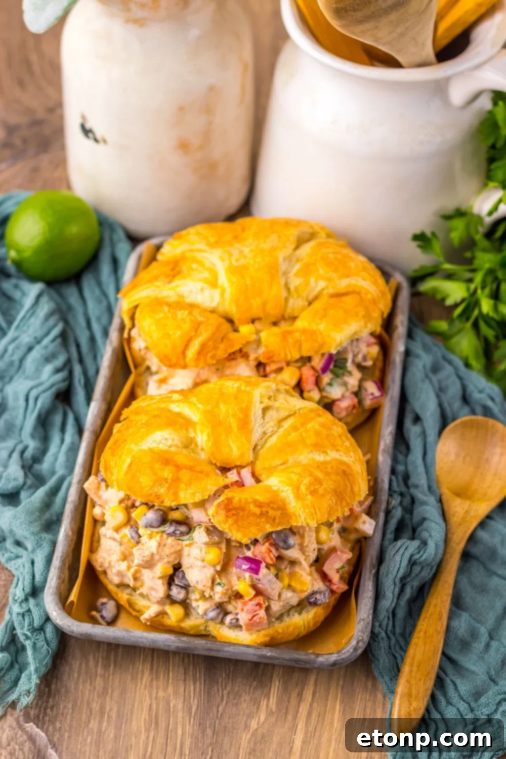 Overhead view of Creamy Taco Chicken Salad sandwiches arranged on a tray, with lime and cilantro garnishes on the side.