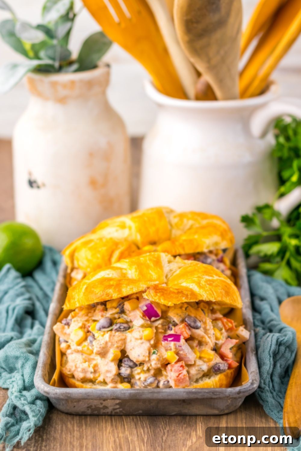 Creamy Taco Chicken Salad nestled in croissants, beautifully arranged on a wooden tray with serving spoons