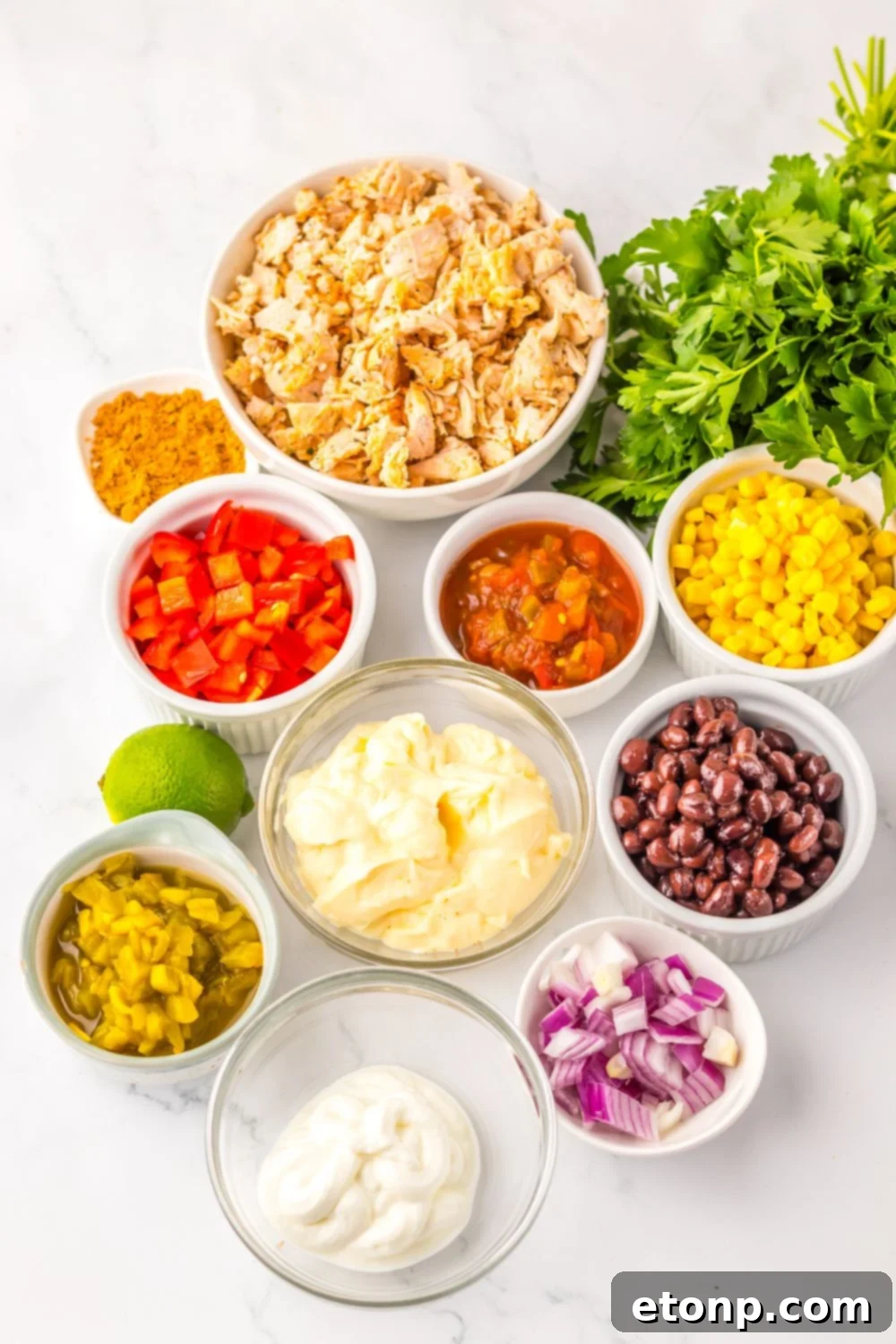 Ingredients for Creamy Taco Chicken Salad displayed in individual bowls on a rustic wooden table.