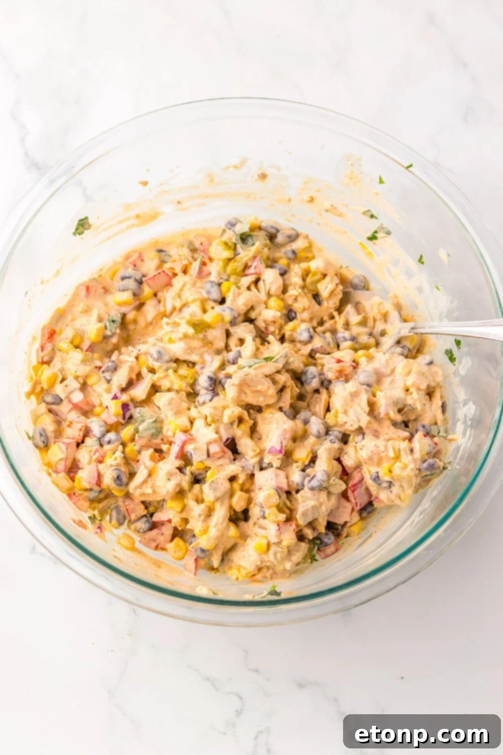 Creamy Taco Chicken Salad in a clear glass bowl, fully mixed and ready to serve.