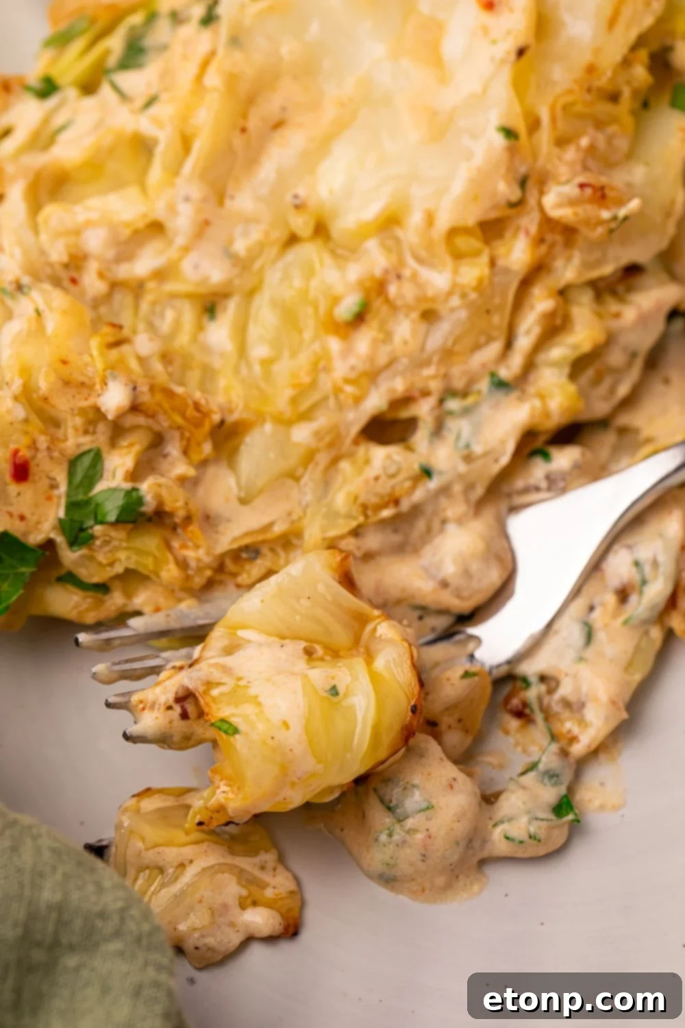 Creamy Garlic Parmesan Cabbage on plate with a fork with some cabbage on it 