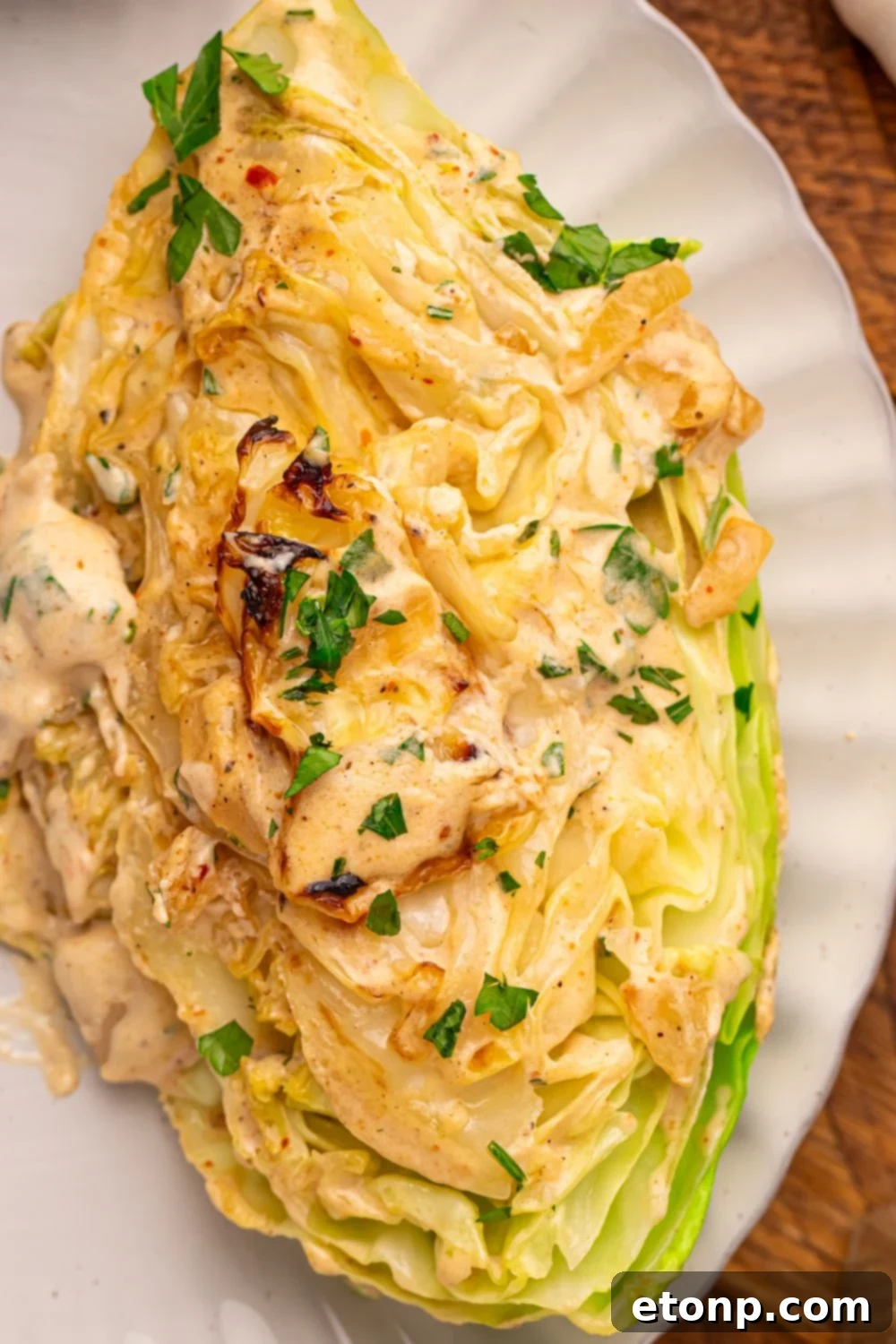 Creamy Garlic Parmesan Cabbage wedge on a plate topped with some parsley 