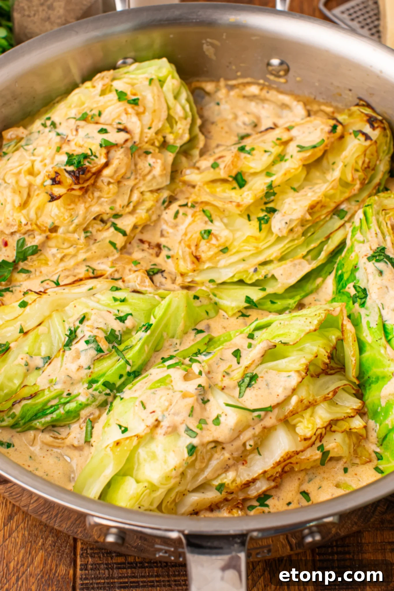 Creamy Garlic Parmesan Cabbage wedges in a skillet topped with cream sauce 