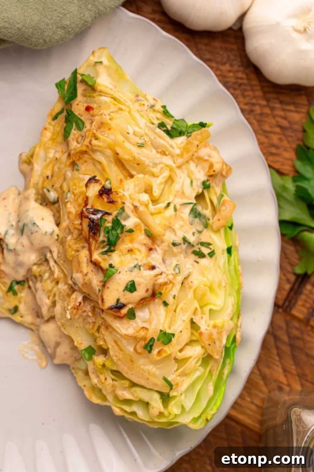 Creamy Garlic Parmesan Cabbage wedge on a plate topped with a creamy garlic sauce 