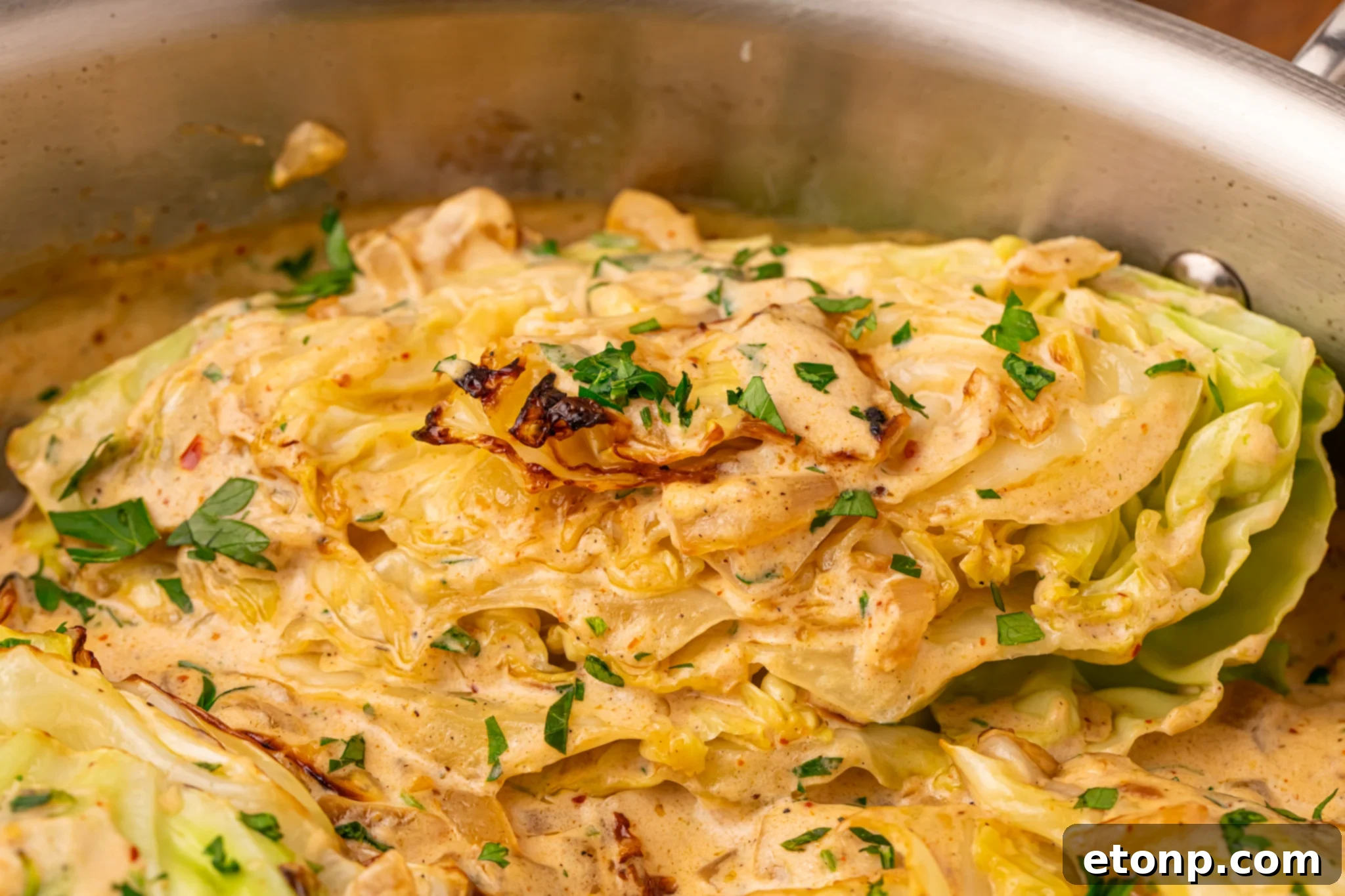 Creamy Garlic Parmesan Cabbage wedge in the skillet topped with some parsley 